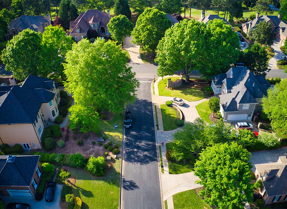 Insurance Solutions - Drone View of a Quiet Wealthy Residential Suburb with Multi Story Homes Surrounded by Vibrant Green Trees